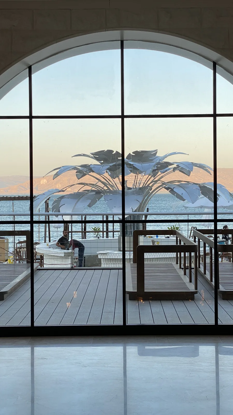 The Bird of Paradise through the arched glass of the hall, against the sunset over the water.
