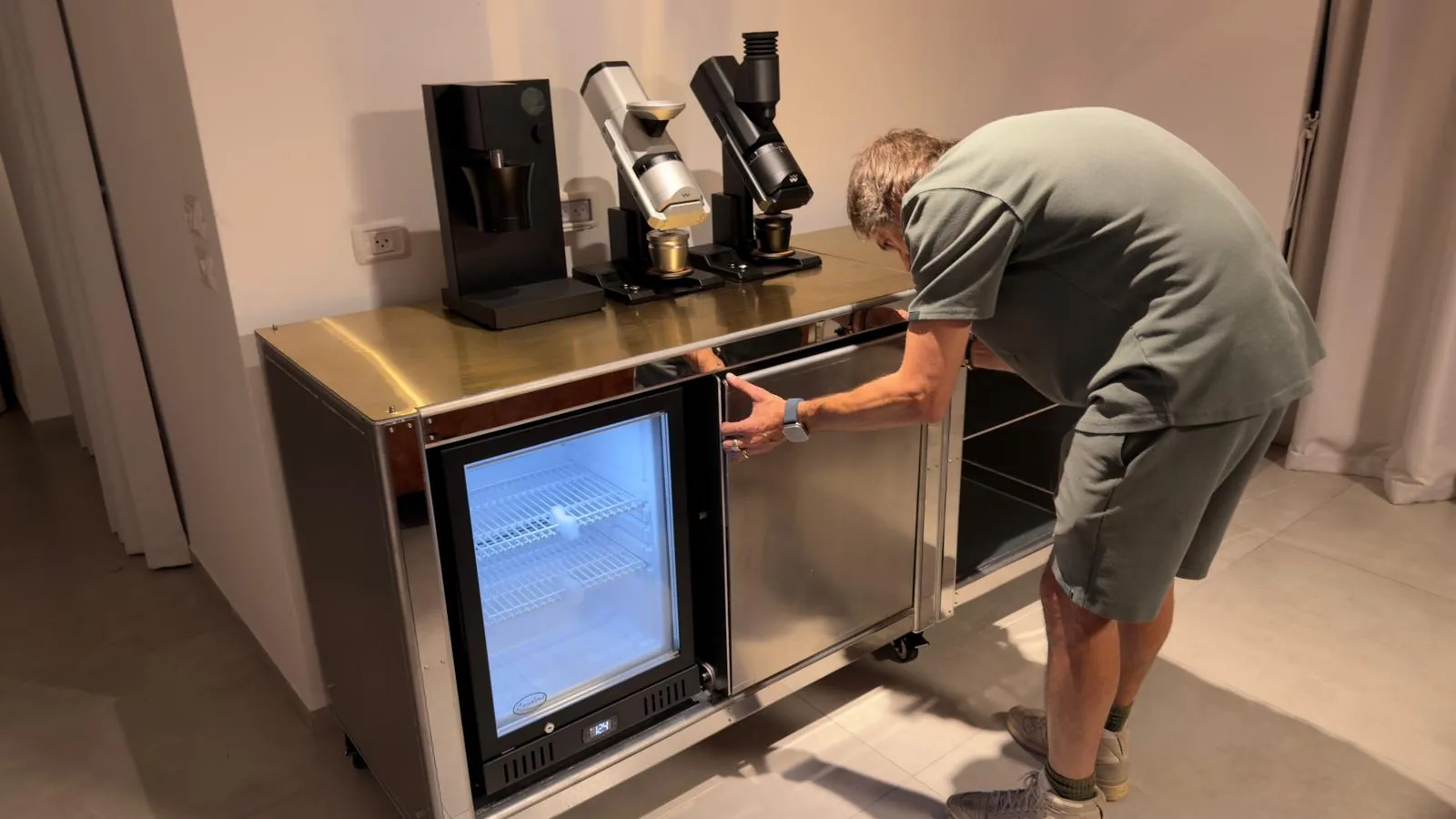 Gilad Kenan adjusting the end bay of the finished Cube Coffee bar on site, display lit.