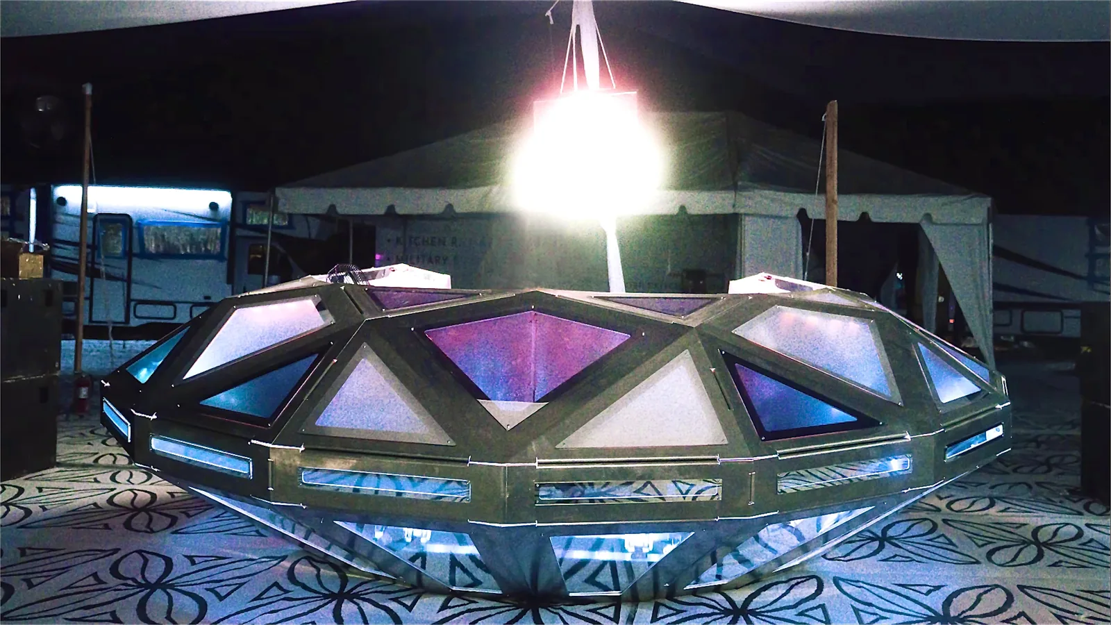 The Diamond UFO lit at the festival — fifty-five frosted facets glowing around the deck. A frame from video, not a photograph.