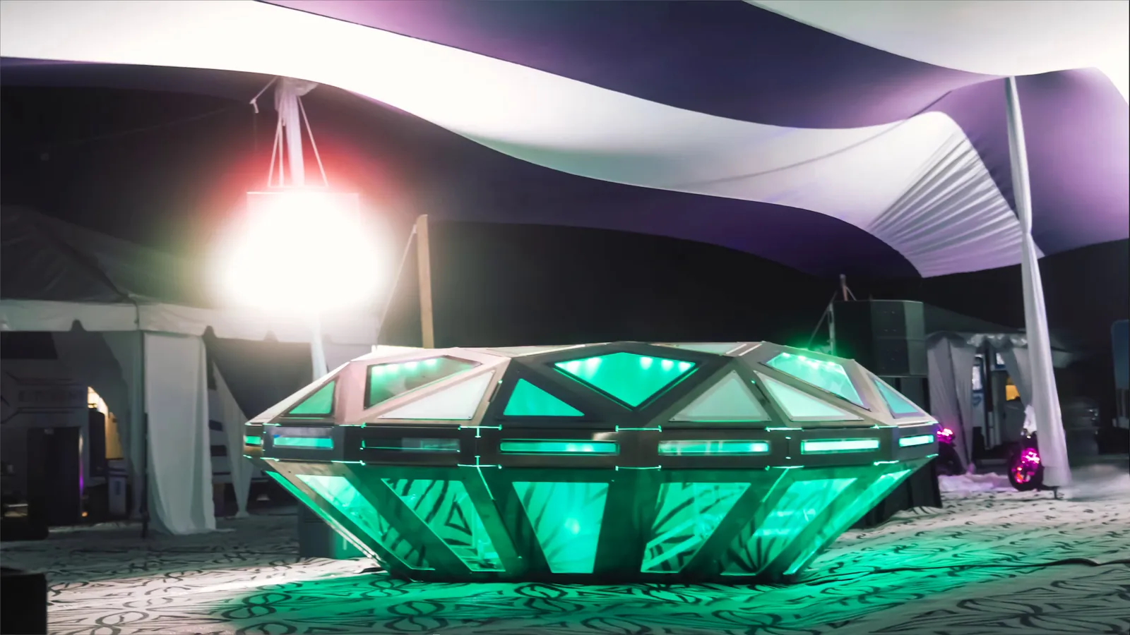 The Diamond UFO lit at the festival — fifty-five frosted facets glowing around the deck. A frame from video, not a photograph.