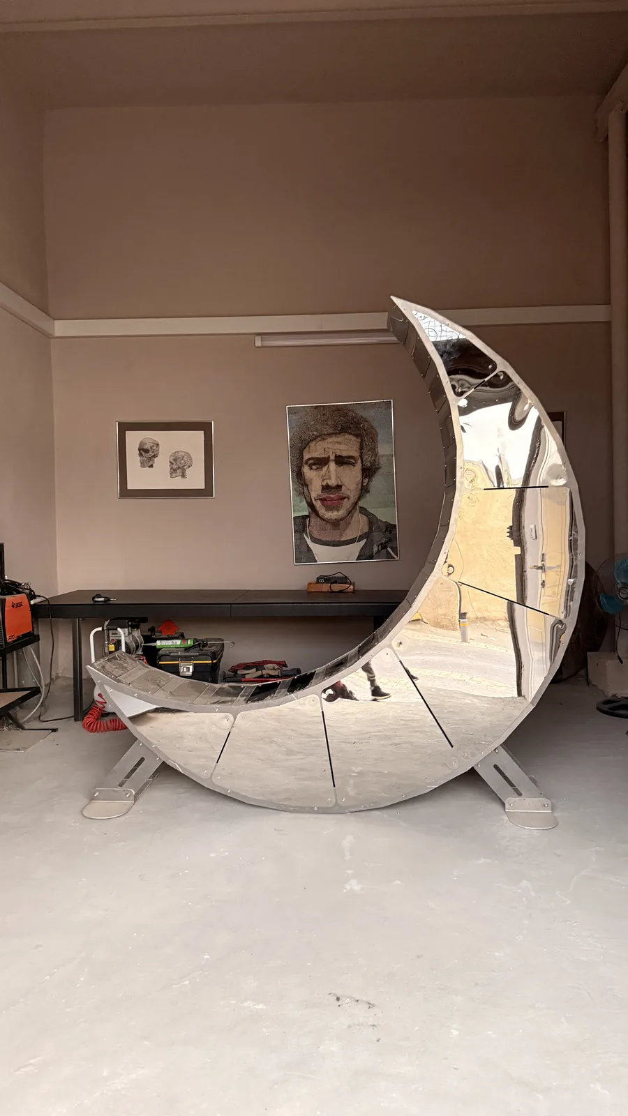 Moon Chair in the workshop — mirror skin over a riveted aluminum spine.