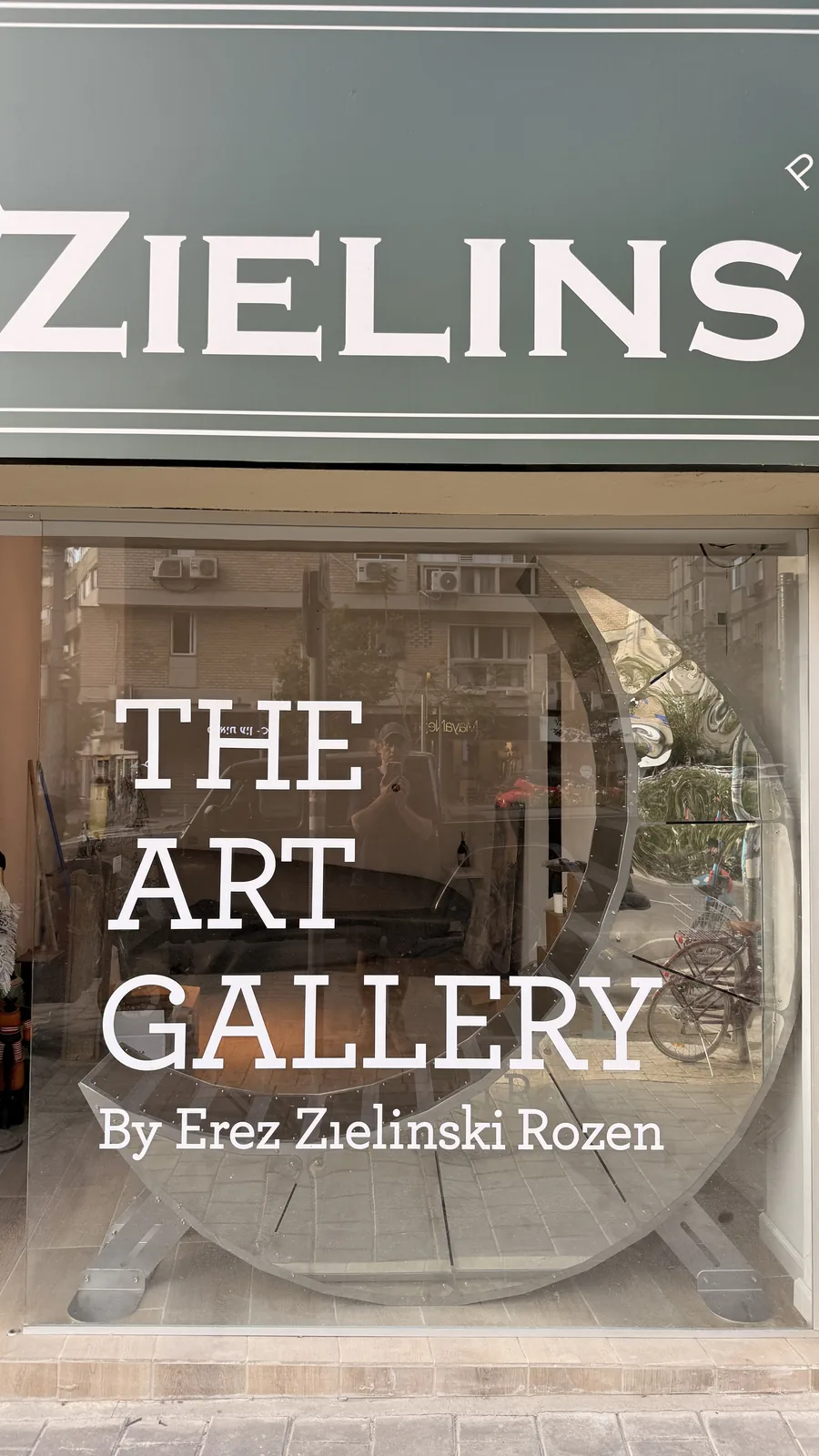 Moon Chair in a gallery window, the crescent behind hand-painted lettering.
